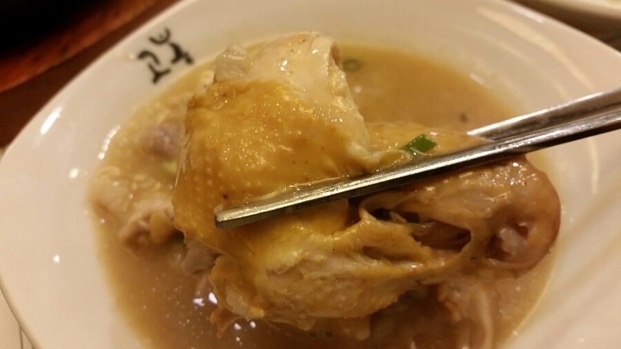 Traveler separating tender samgyetang chicken with chopsticks