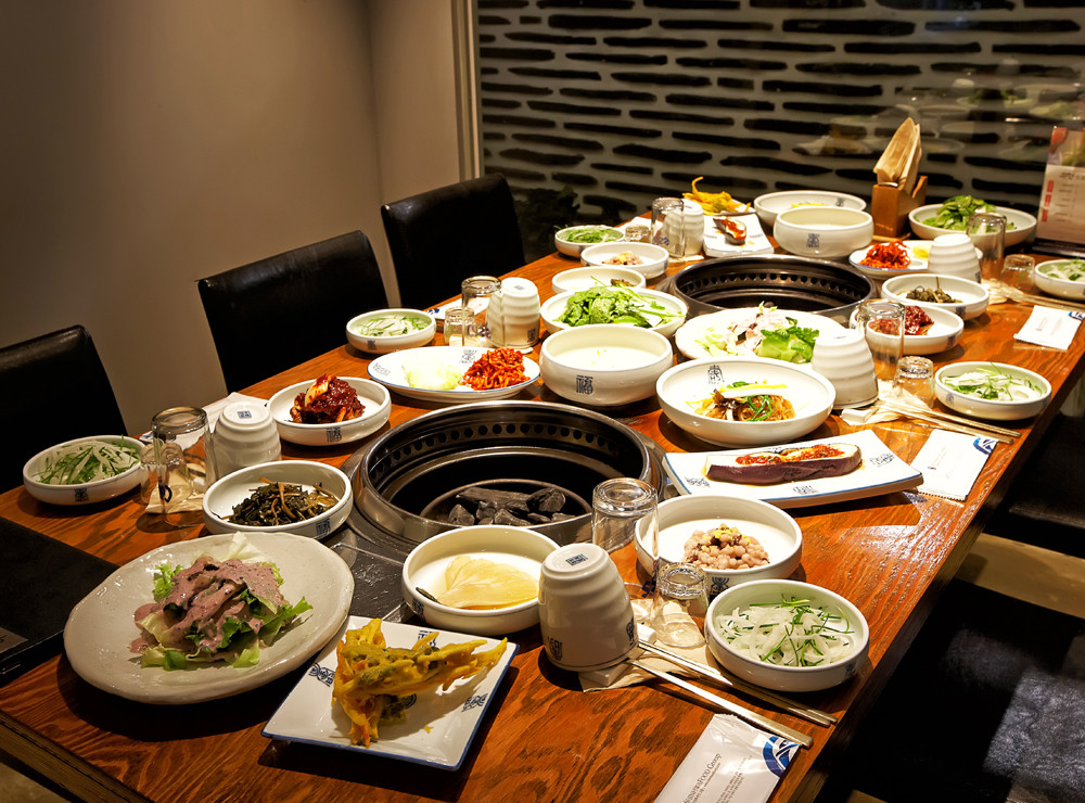 Two people sharing Korean BBQ with lettuce wraps and side dishes